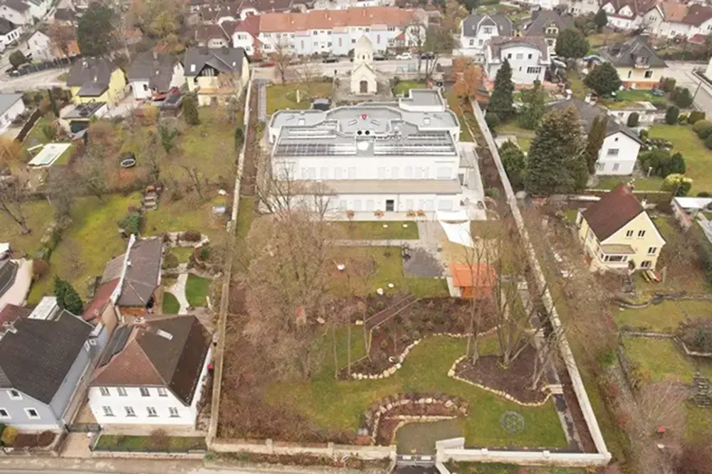  Luftaufnahme einer kleinen Stadt mit einer Kirche und einem Garten im Vordergrund.