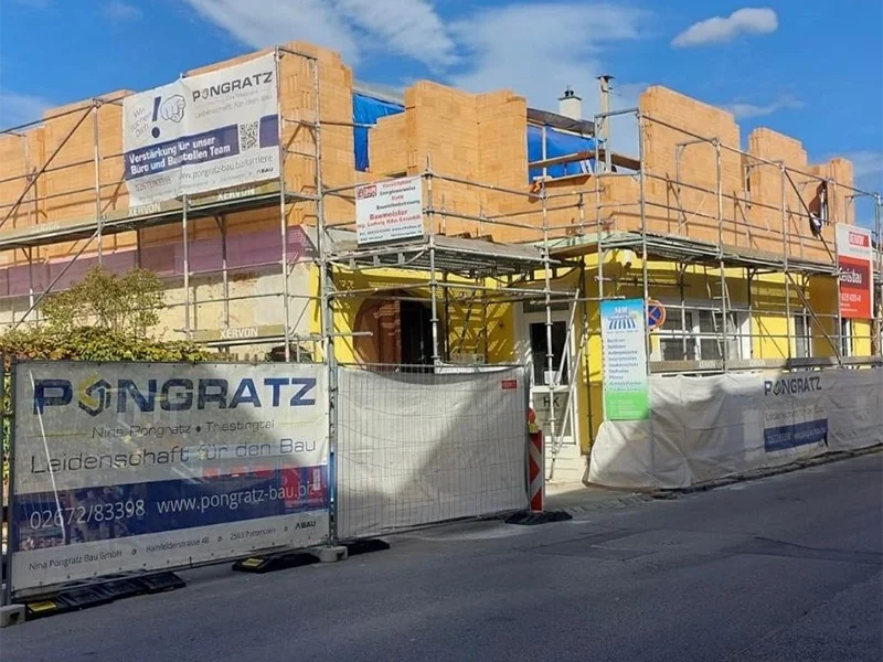 Gelbes Haus mit Gerüst an der Seite, das für Renovierungsarbeiten vorbereitet ist.